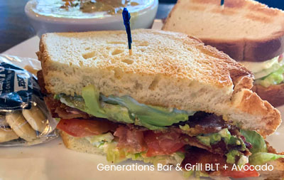 A Generations Bar Grill sandwich with bacon, lettuce, tomato, and avocado, served with fries and a cup of soup.