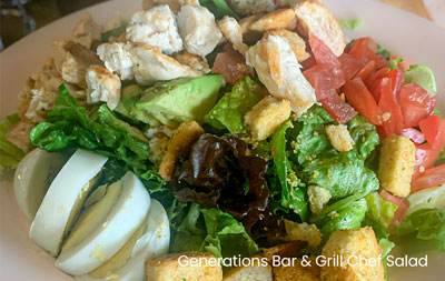 A plate of Generations Bar Grill Sherwood's chef salad with chicken, avocado, and sliced eggs.