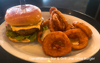 A Line Drive burger with onion rings on a plate, showcasing a $15 meal from Generations Bar Grill on Sherwood.